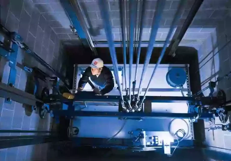 Workers installing guide rails and calibrating alignment in the elevator shaft during construction.