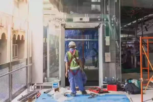 A passenger elevator installation site showing hoistway preparation and equipment setup.