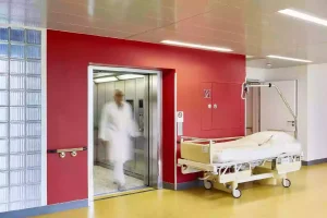 Heavy-duty service elevator in use at a hospital, designed for transporting medical equipment and beds.